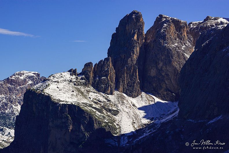The Torre Orientale Meisules dala Biesces, part of the Sella Group mountain massif, rises up from the Sella Pass against a blue sky